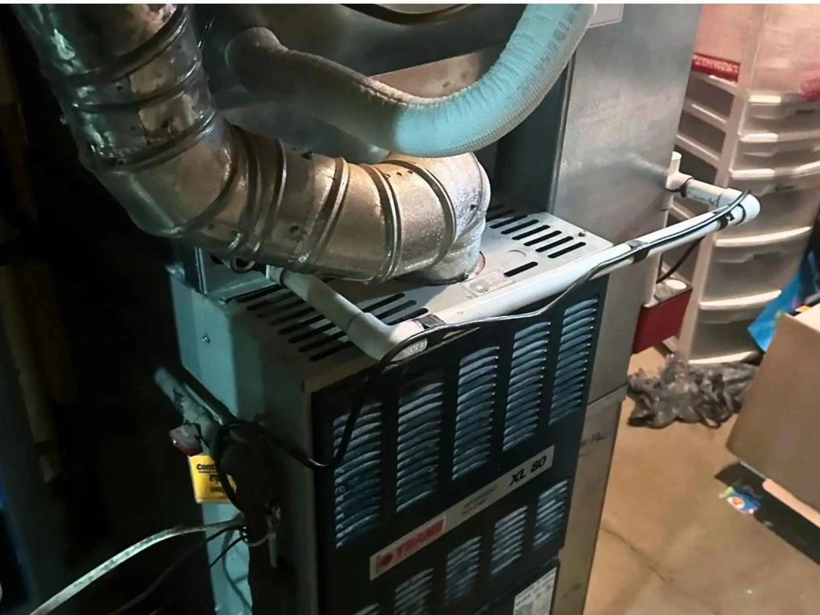 Residential gas furnace with metal exhaust venting and ductwork in a utility room.